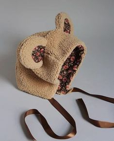 a teddy bear purse sitting on top of a white table next to a brown ribbon