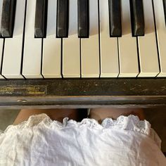 a person sitting at a piano with their feet on the keyboard and looking down from above