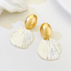 ✦ Indulge in the feminine elegance of our Textured Two Tone Abstract Fan-Shaped Shell Drop Earrings. With a unique fan shape and textured abstract design, these earrings exude a vacation summer feel. Choose between matte gold or glossy gold pendants to match your personal style. Perfect for a beach vacation, these high quality earrings will surely get you compliments. ----------- DETAILS----------- - *Sold in Pair - Color: Gold & Silver - Pattern: Matte Gold/ Glossy Gold - Glossy Gold (Length* Width): 4.2cm * 2.5cm - Matte Gold (Length* Width): 4.4cm * 2.5cm - Materials: 925 Sterling Silve, Brass - SKU: R2690 Shell-shaped Metal Earrings, Metal Shell-shaped Earrings, Gold Shell-shaped Earrings For Party, Elegant Shell-shaped Metal Earrings, Elegant Shell-shaped Earrings, Feminine Elegance, Gold Pendants, Retro Earring, Matte Gold