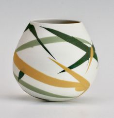 a white vase with green, yellow and brown lines on it's rims