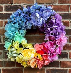 a multicolored wreath on a brick wall with flowers in the shape of a letter o