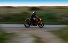 a man riding on the back of a motorcycle down a road