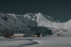 a snow covered mountain with houses in the foreground and trees on the other side