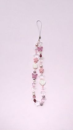 a necklace with beads and charms hanging from it's side on a pink background