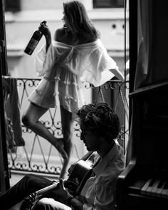 a man sitting in front of a piano next to a woman standing on the balcony