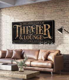 a living room with a couch, coffee table and large sign on the wall that says theater & lounge