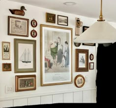 a wall with many pictures on it and a lamp hanging from the ceiling in front of them