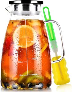 a pitcher filled with liquid and fruit next to a measuring cup on a white background