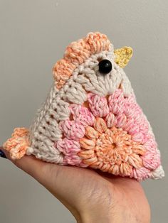 a small crocheted bird is sitting on someone's hand and it looks like they are holding something