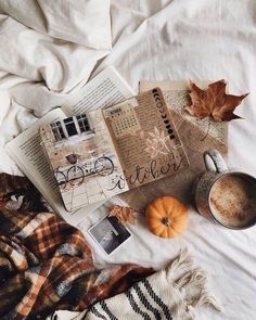 an open book, cup of coffee and some other items on top of a bed