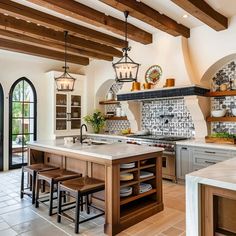 a large kitchen with lots of counter space and hanging lights over the stove top oven