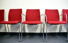 four red chairs lined up against a white wall