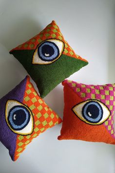 three decorative pillows with an eye on them