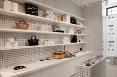 a white tiled bathroom with shelves filled with purses