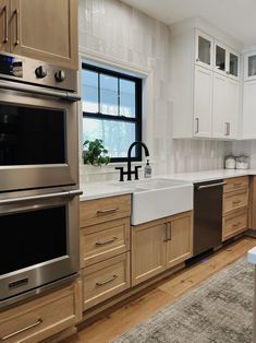 a clean kitchen with stainless steel appliances and wood cabinets, along with an area rug on the floor