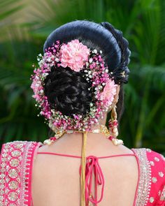 the back of a woman's head with pink flowers in her hair and braid