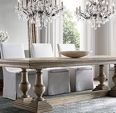 a dining room table with white chairs and chandelier