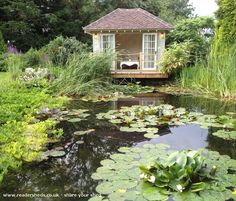 a gazebo sitting on top of a lush green field next to water lilies