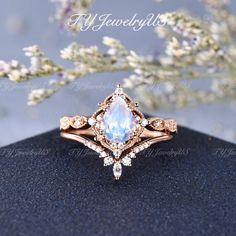 an engagement ring with a pear shaped blue stone surrounded by small white and pink diamonds