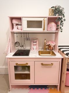 a toy kitchen with pink furniture and accessories