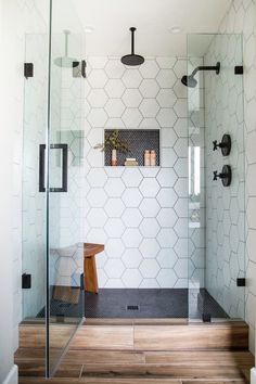 a bathroom with a glass shower door and wooden stool next to the shower stall area