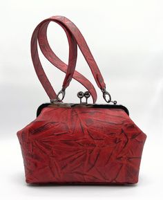 "Red Leather Kiss Lock Handbag is a fashionable must have in your collection. Combination of textured Leather, black nickel hardware and wide shoulder strap makes it unique.  The small Women's Handbag is perfect for every day. This Kiss Lock Closure Bag is One of a Kind . Floral Cotton Lining and two pockets inside. Perfect for your cell phone, wallet, makeup and keys. Long Shoulder Strap. Ready to Ship. 100% Handmade BAG MEASUREMENTS Height: 7.1\" Width: 9,4\" bottom Depth: 4\" Strap Drop: 20,5 Red Textured Leather Top Handle Shoulder Bag, Red Top Handle Clutch For Daily Use, Textured Leather Crossbody Evening Bag For Everyday Use, Red Textured Leather Shoulder Bag For Evening, Everyday Textured Leather Crossbody Evening Bag, Red Textured Leather Rectangular Bag, Red Textured Leather Shoulder Satchel, Red Textured Leather Rectangular Satchel, Kiss Lock Purse