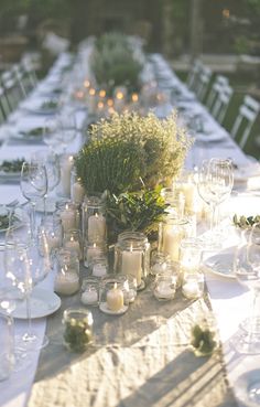 a long table is set with candles and greenery