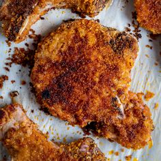 some fried meat is sitting on a piece of parchment paper with seasoning sprinkles