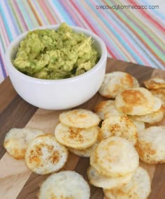 some food is sitting on a cutting board next to a bowl of guacamole