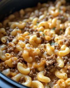 a crock pot filled with macaroni and cheese covered in ground beef sauce