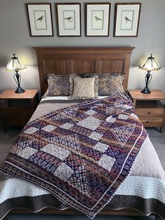 a bed with two lamps on either side of it and three pictures above the headboard