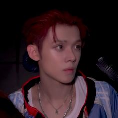 a young man with red hair is staring at the camera