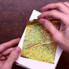 two hands holding an open photo album with gold glitter on the cover and white paper