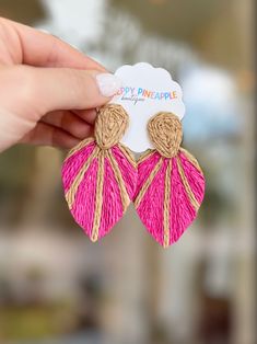 a pair of pink and gold tasseled earrings with the words happy pineapple on it