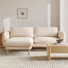 a white couch sitting on top of a rug next to a wooden coffee table in a living room