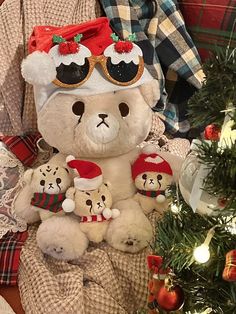 a white teddy bear sitting on top of a pile of stuffed animals next to a christmas tree