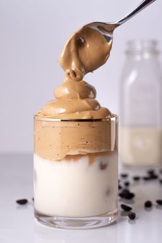 a spoon with some food in it on top of a glass jar filled with pudding