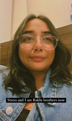 a woman with glasses and a denim jacket is looking at the camera while she's smiling