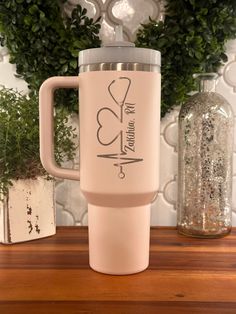 a pink travel mug with the words love and hearts on it sitting on a wooden table