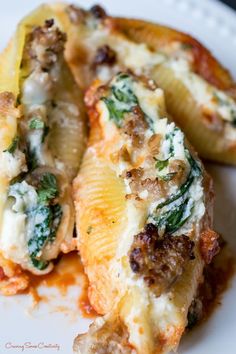 some type of stuffed shells with cheese and spinach on them sitting on a white plate