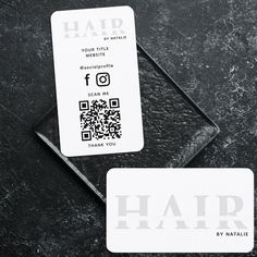 two business cards sitting next to each other on top of a black surface with the word hair printed on it