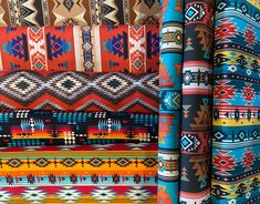 colorful fabrics are lined up in rows and stacked on top of each other with different patterns