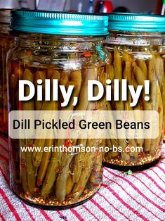 three jars filled with pickled green beans on top of a red and white table cloth