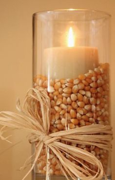 a glass jar filled with corn and a lit candle