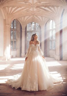 a woman in a wedding dress is standing in an old building with sunlight streaming through the windows