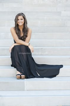 a woman sitting on some steps wearing a black dress