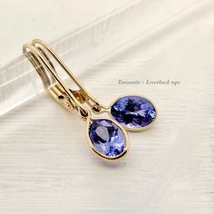 A Violet purple blue oval Tanzanite in a simple 14k gold bezel suspended from your choice of, lever backs, thin round hoops, or diamond tops. Select the style you love the most. All made with ethical genuine gemstones and recycled solid 14k gold Genuine Tanzanite approximately .60 - .70 carats each oval-cut 6.5 x 4.5 mm Blue Violet to periwinkle - colors vary Diamonds option: .05 each diamond hoop Solid 14 karat yellow gold Made to order - 1 week production time Select your option: :: Style 1: T Oval Tanzanite Earrings, Tourmalated Quartz Ring, Unique Diamond Wedding Bands, Watermelon Tourmaline Ring, Diamond Tops, Tourmalated Quartz, Pink Sapphire Ring Engagement, December Birthstone Ring, Tanzanite Earrings