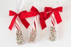 three candy canes wrapped in cellophane with bows