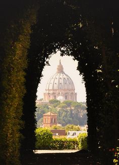 an arch leading to a domed building with trees in the foreground