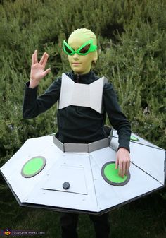 a man dressed in an alien costume with green eyes and hands out to the camera